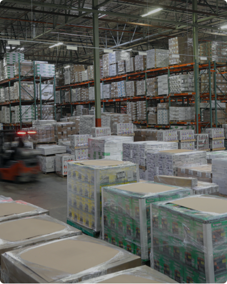 "A well-organized warehouse with stacked pallets, shelves filled with products, and a forklift in motion, showcasing efficient just-in-time inventory management and logistics."